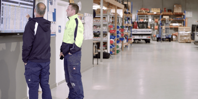 Two tradesmen using Fergus job management software in warehouse
